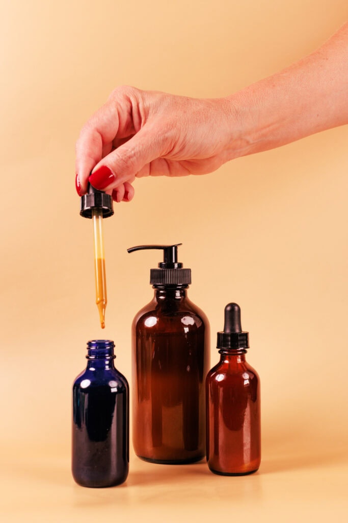 Vial and dropper bottles filled with skincare formulas and oils on yellow background for cosmetic formulations and beauty products.