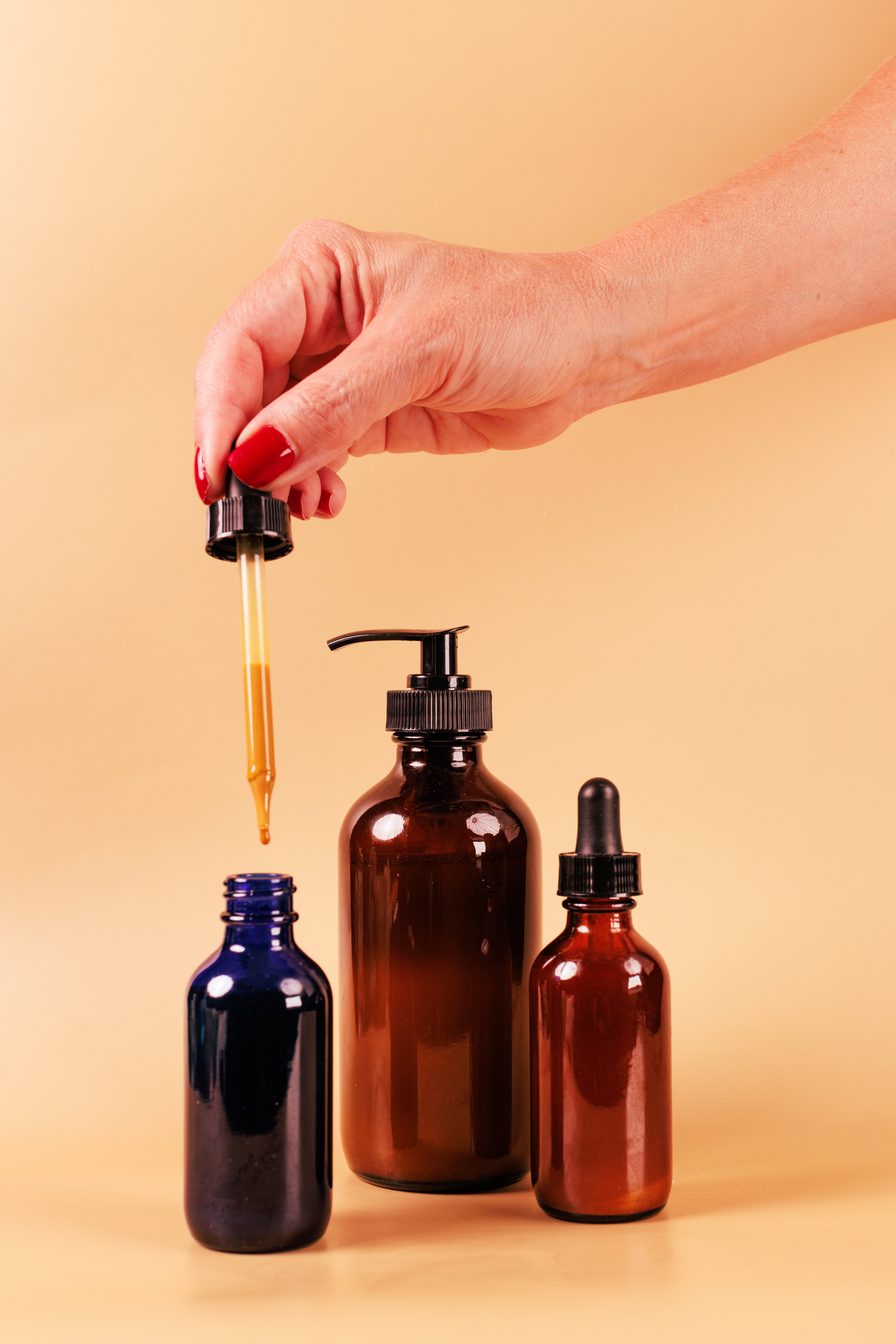 Vial and dropper bottles filled with skincare formulas and oils on yellow background for cosmetic formulations and beauty products.