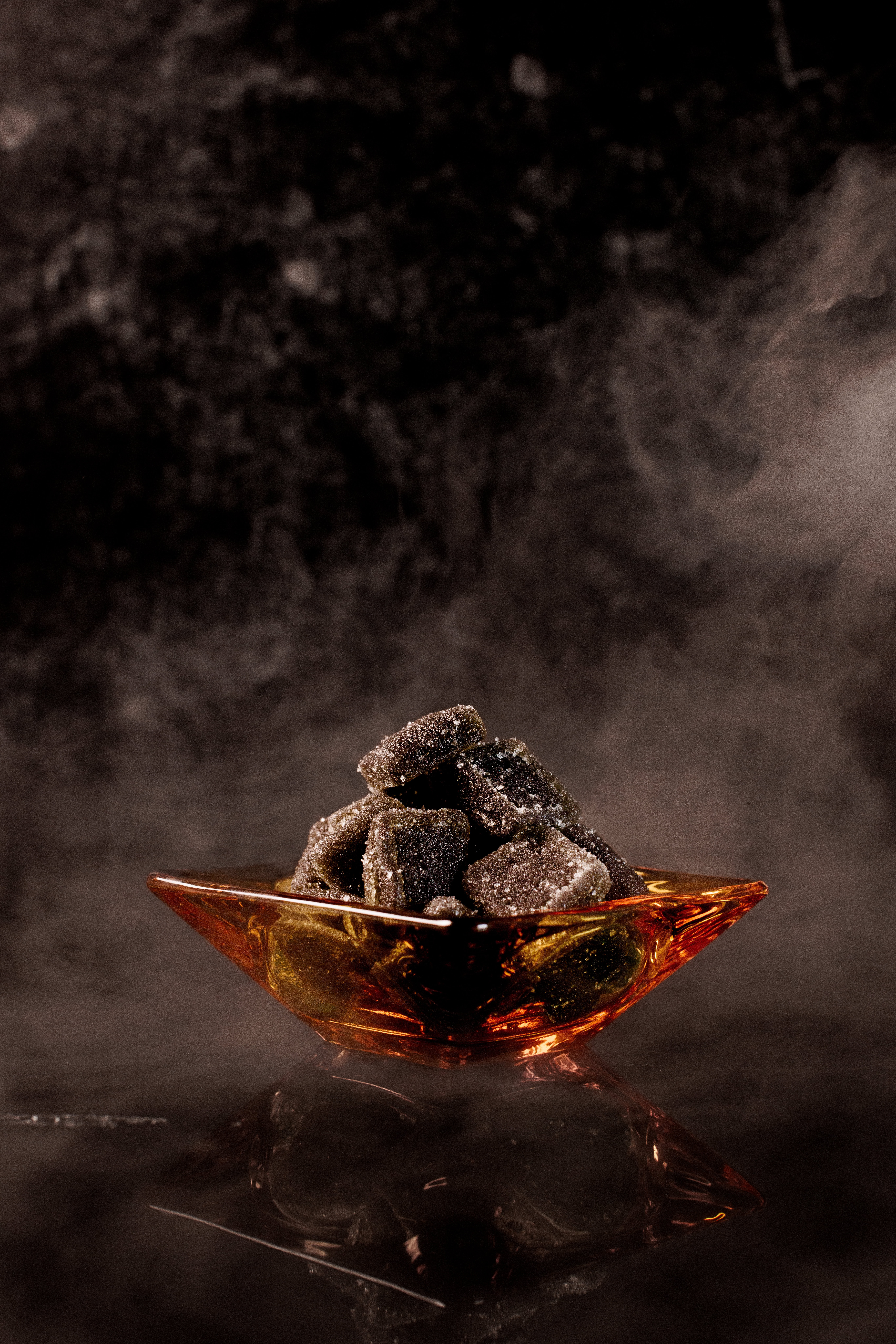 Succulent black bear-shaped gummies coated in sugar in a sleek glass dish, representing innovative formulation solutions by Structure Formulations.