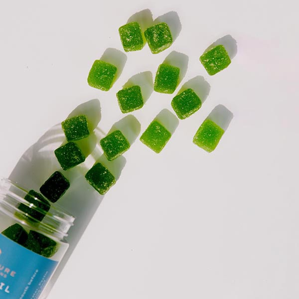 Sugar-free green gummy vitamins spilling from a bottle, emphasizing healthy supplement options.