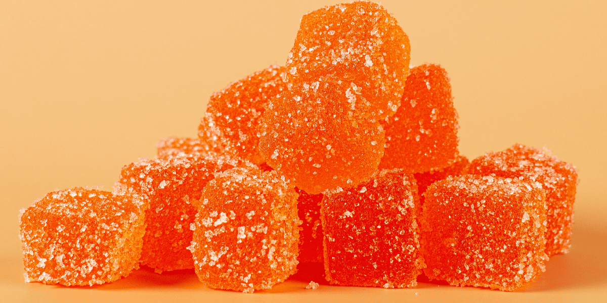 Orange gummy candies coated in sugar, showcasing confectionery and gummy supplement manufacturing. Perfect for promoting dietary supplements and functional food ingredients.